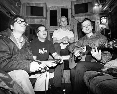 A monochrome photo of the four men, in their 20s, in a room full of TVs