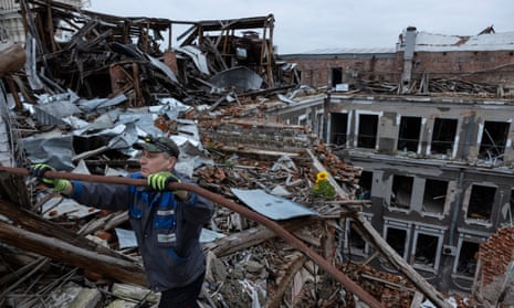 A security guard clears debris on the rooftop of a building in Kharkiv amid the ongoing war with Ukraine
