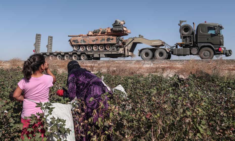 Agricultural workers watch Turkish military vehicles on the way to northern Syria.