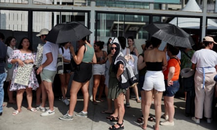 Women protect themselves from the sun as they stand in a queue on Thursday outside the stadium where the Taylor Swift concert took place in Rio de Janeiro, Brazil, on Friday.