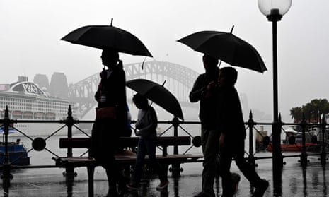 Pedestrians in the rain silhouetted against the Sydney harbour bridge