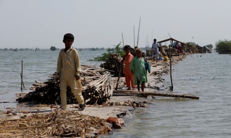 Children take refuge along a damaged road amid flooding in Sehwan, Pakistan, in early September.