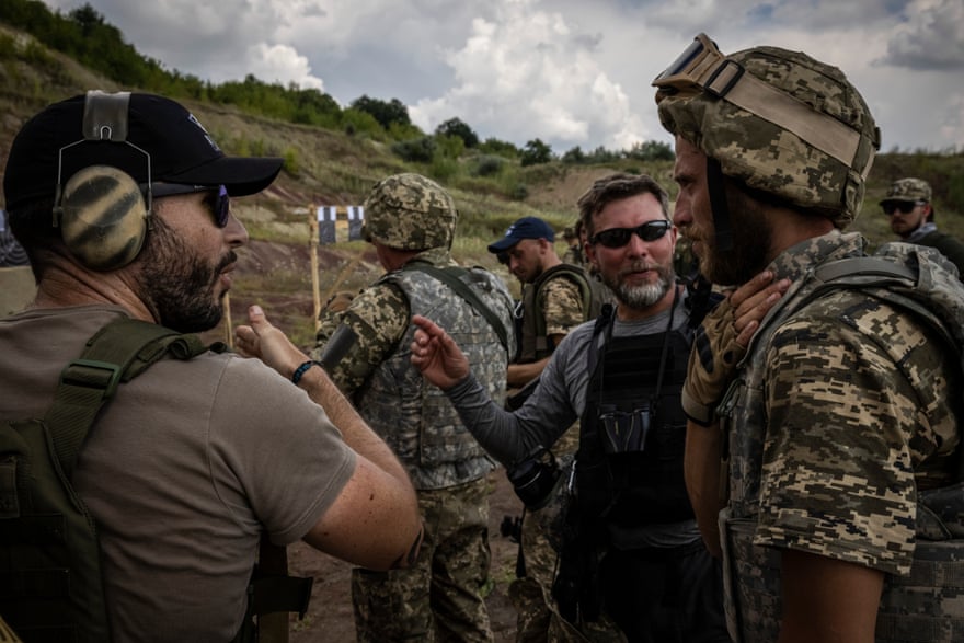 An interpreter, center, mediates between a trainer, left and soldier