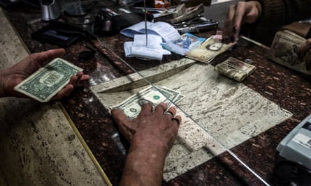 A customer receives US dollars during a transaction at an Italcambio currency exchange house in Caracas.