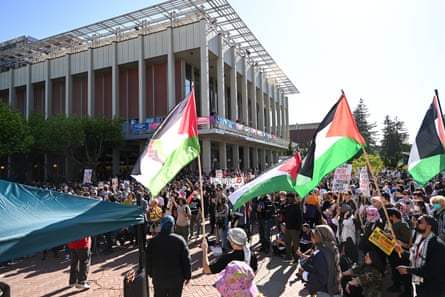 people stand with palestinian flags outside the same building, shot from the same angle, in a color photo