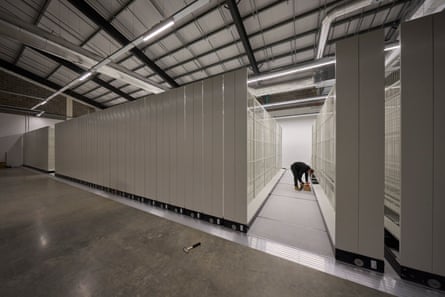 A huge number of all-white sliding storage shelves with someone working on one in the near distance.