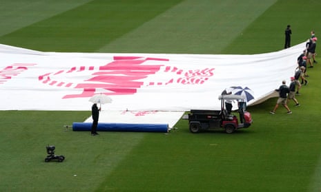 Grounds workers cover the wicket as rain begins to fall during the third Test between Australia and Pakistan