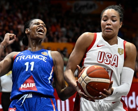France's Valeriane Ayayi celebrates, fist raised, beside a USA player holding the ball