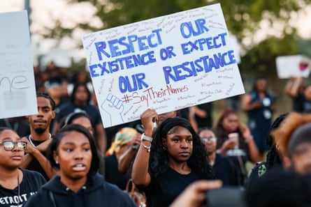 A young woman holds a sign saying 'Respect Our Existence of Expect Our Resistance' among other protestrs.