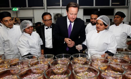 Former British Prime Minister David Cameron is shown around the kitchen by the founder of the British Curry Awards, Enam Ali, centre left, at the 2013 awards ceremony in London.