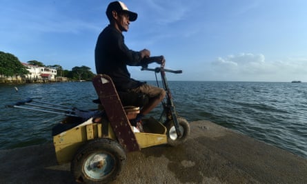 Disabled diver Ernesto McLean rides a makeshift handicapped cart as he watches the sea in Puerto Lempira, Honduras.