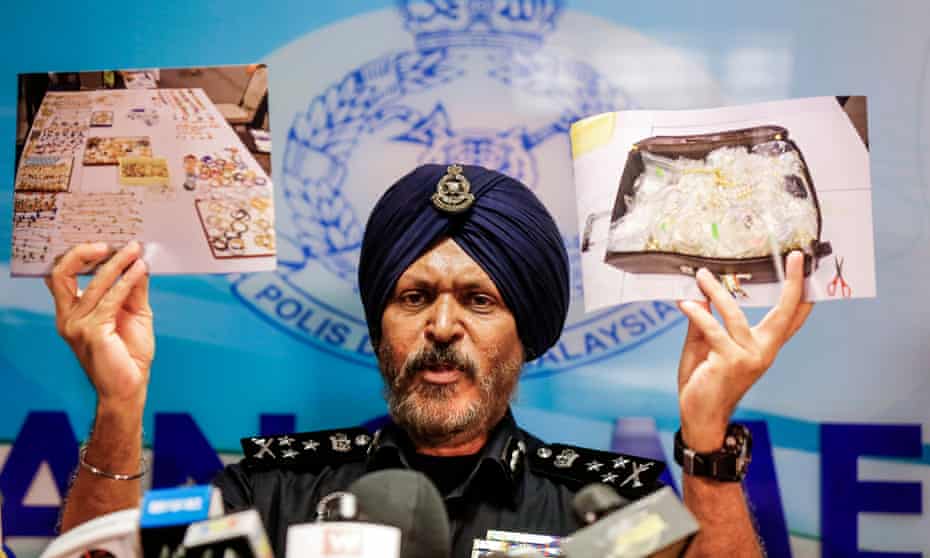 A Malaysian police director shows a photograph of items collected during a raid on Najib Razak’s homes.