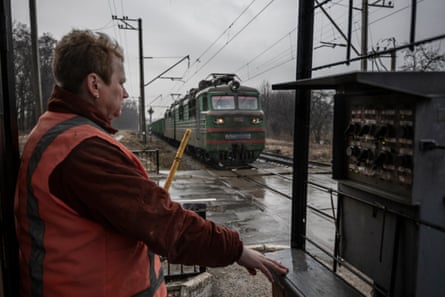 Nadiya Neschcheryakova at her post at a railway crossing in Bucha, near Kyiv. A freight train approaches under an overcast winter sky.