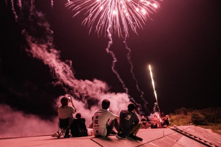 People watch the fireworks on a seawall reconstructed after the tsunami hit in 2011, in Minamisoma, Fukushima prefecture on August 1, 2021
