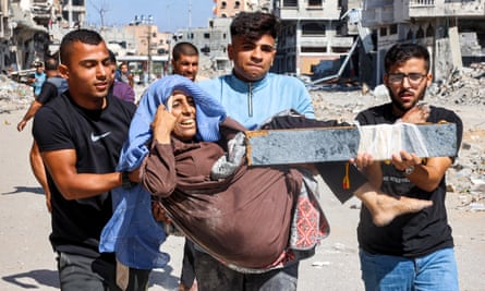 Men carry an injured woman who has a makeshift splint on a leg