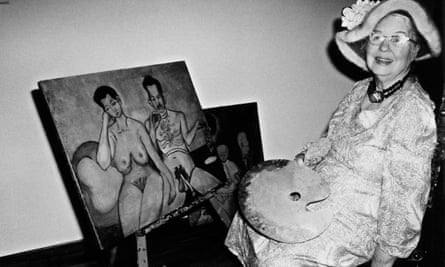 Alice Neel portant un chapeau mou et assise à côté d'une peinture finie de deux nus