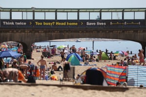 Boscombe, Dorset Sunbathers relax under a coronavirus warning sign near the pier
