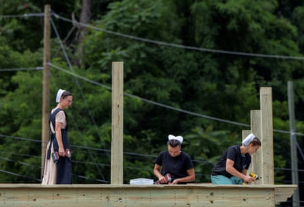 Three young Amish women building the frame of a house