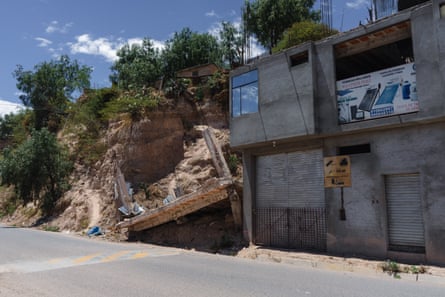 A house destroyed by a landslide next to a boarded up building.