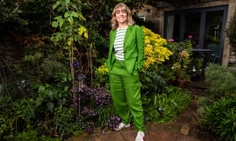 Claudia Hammond in her back garden, wearing a bright green casual trouser suit and a green and white striped top