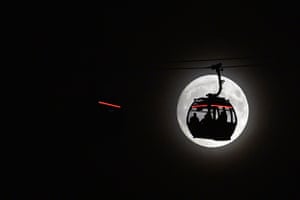 The moon rises behind a cable car in the Docklands