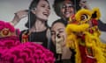 A woman takes photos as traditional Lion dance performers dance 