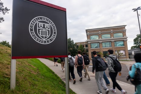 Students with backpacks walk along a path on Cornell University's campus