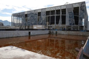 Translucent tapestries created by the Brazilian artist Adriana Varejao, fall from the exterior of the aquatics centre as a combination of mud, rainwater and dead insects have contributed to the rust colour of the water in a practice pool