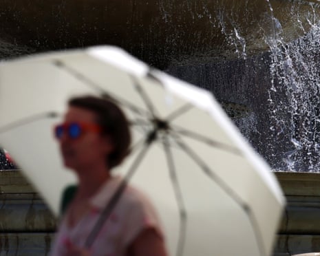 A pedestrian uses an umbrella to shelter from the sun, in London, Britain.