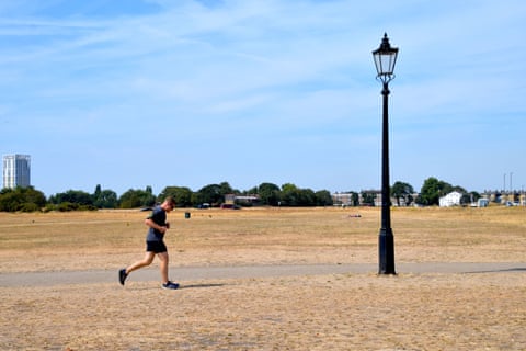 A person runs across parched parkland
