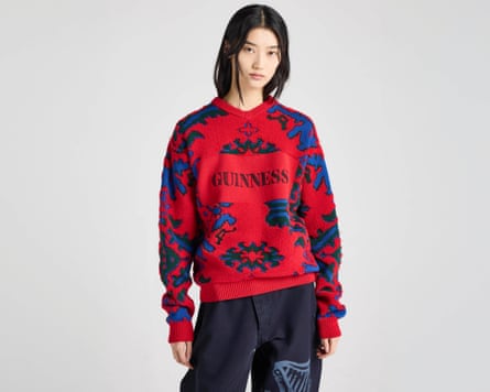 A model wears the unisex JW Anderson X Guinness ‘pub carpet jumper’ in navy and red, with Guinness logo