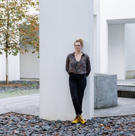 A woman stands in front of a white pillar.