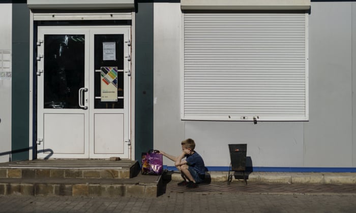 Un niño espera a su madre afuera de una de las pocas tiendas que aún están abiertas en Sloviansk, región de Donetsk, este de Ucrania, el 6 de agosto de 2022.  (Foto AP/David Goldman)