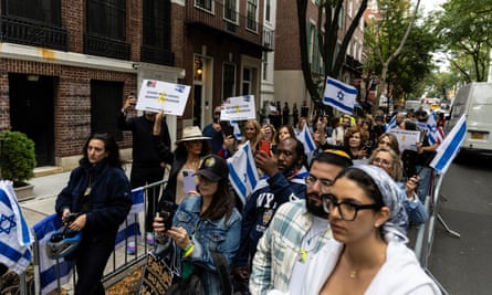 People hold Israeli flags within metal barriers on a street