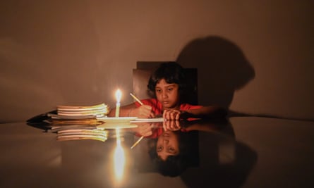 A child studies besides a lit candle at her residence during a power cut in Biyagama, a suburb of the capital Colombo