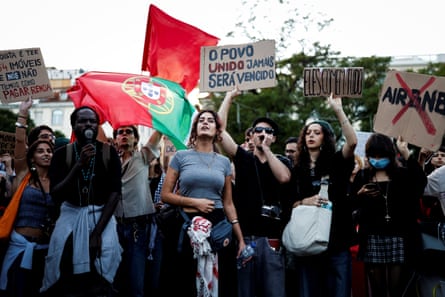 Protesters holding signs and a Portuguese flag