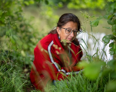 A woman in red jacket crouching in the grass