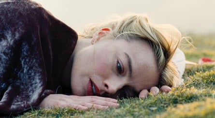 Margot Robbie in Wuthering Heights. She is lying down in closeup on a grass slope