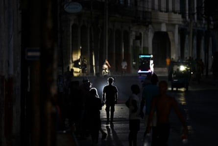 People walk on a street in near darkness in the Cuban capital