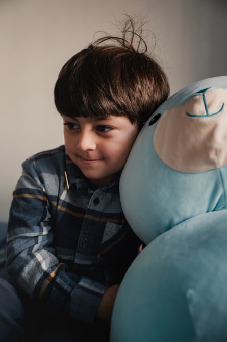 a boy cuddles a blue stuffed animal
