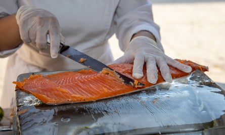 A chef cuts slices of salmon from a large fillet 