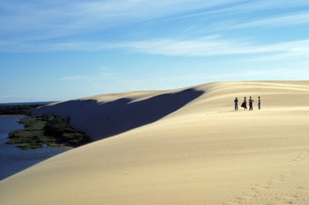 A pristine sand dune with people standing on it in the distance