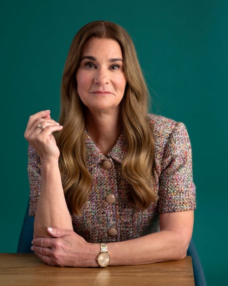 Melinda French Gates gestures is sat at a wooden table and wearing a multicoloured tweed jacket