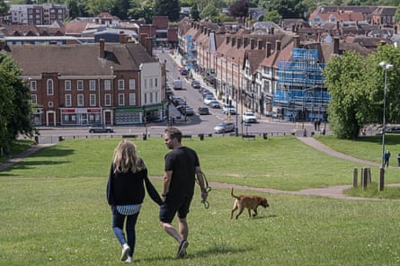 A man and woman walk with a dog towards a town