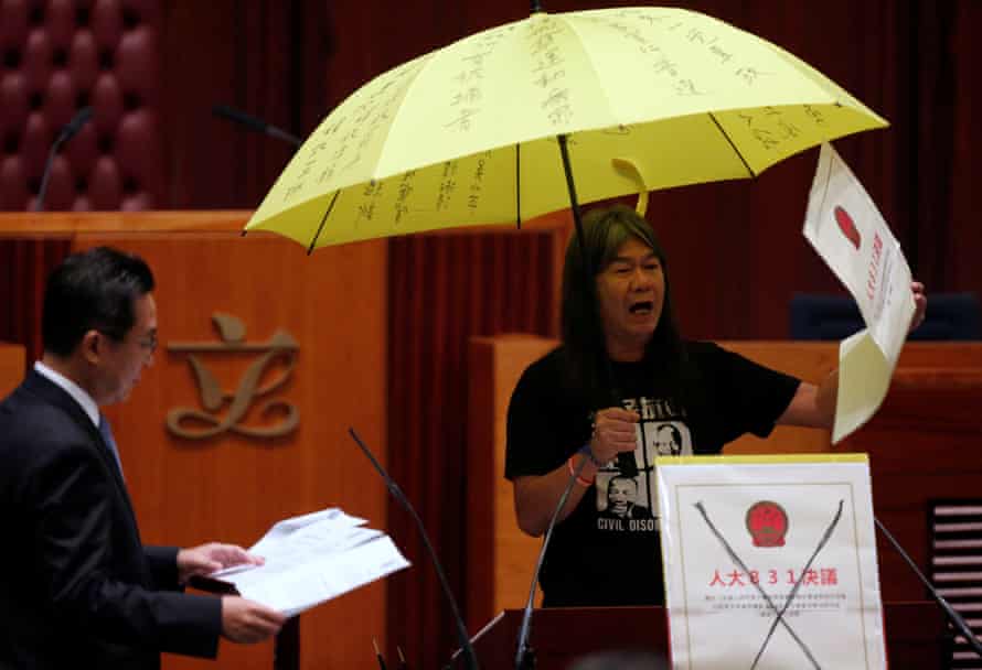 Leung Kwok-hung holds an umbrella while taking his oath at the legislative council.