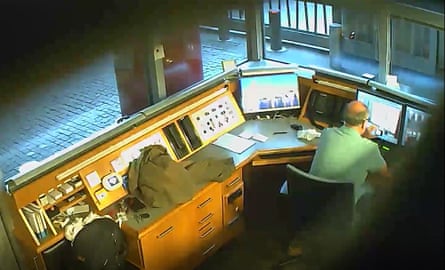 A still from a covert camera shows Smith taking a video of CCTV monitors in the British embassy security kiosk in Berlin