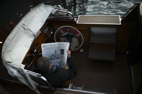 A driver of a tourist boat reads an Italian newspaper with headlines referring to the coronavirus outbreak in Venice.