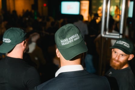 Men wearing green baseball caps with white embroidery that says Make America Healthy Again.