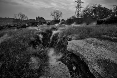 A large fissure in the ground with smoke rising from it