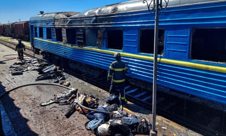 Firefighters beside a passenger train damaged in a Russian strike in Kherson on Wednesday